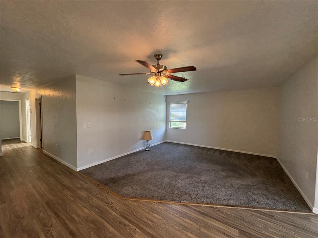 A living room features a carpeted area, wood-look flooring, and a ceiling fan — 3276 BRUNSWICK LANE UNIT 705, SARASOTA, FL