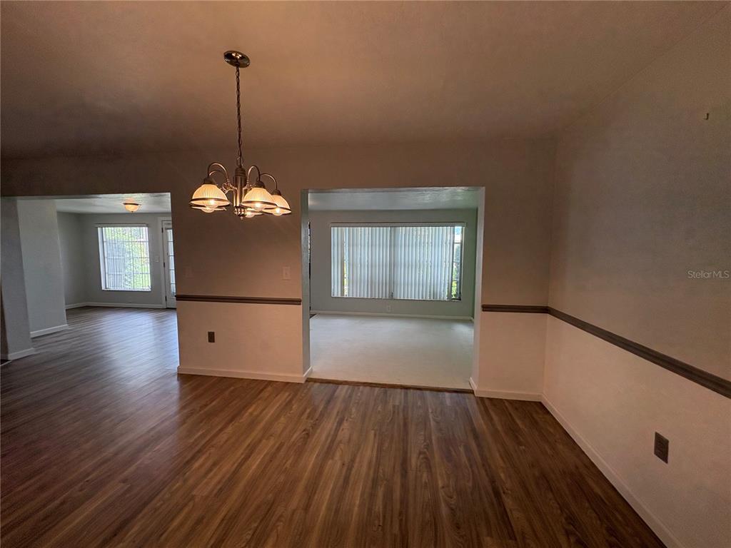 An interior view shows a dining area with wood-look flooring and a chandelier — 3276 BRUNSWICK LANE UNIT 705, SARASOTA, FL