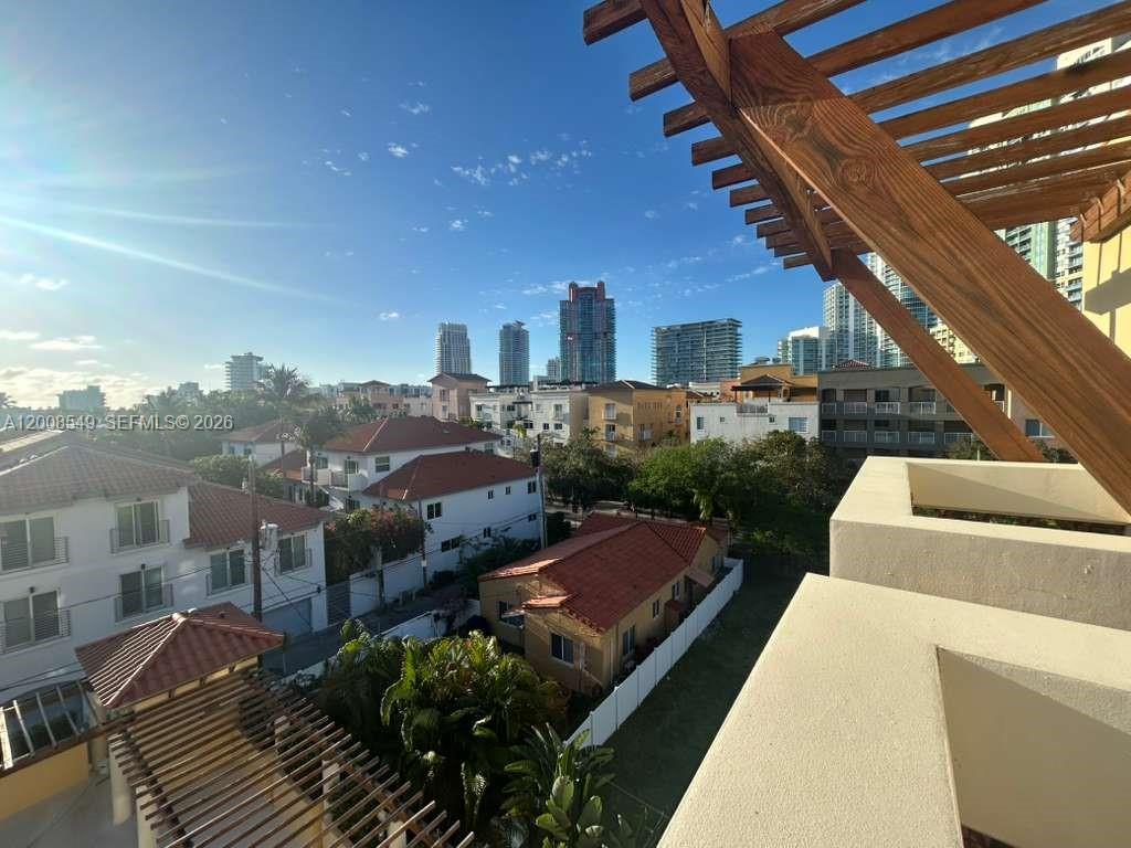 An elevated view from a balcony overlooking a residential neighborhood and distant city skyline — 227 Michigan Ave # 502, Miami Beach FL 33139, MIAMI BEACH, FL