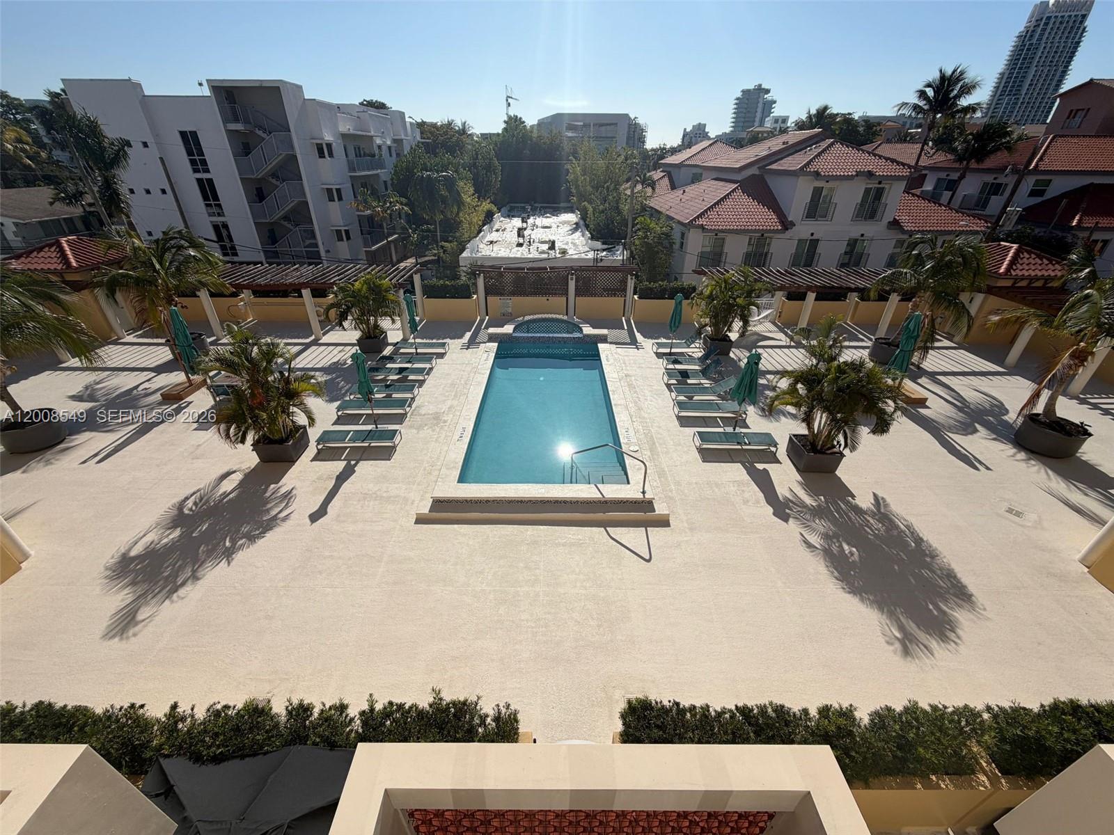 An elevated view shows a rectangular swimming pool surrounded by lounge chairs and palm trees — 227 Michigan Ave # 502, Miami Beach FL 33139, MIAMI BEACH, FL