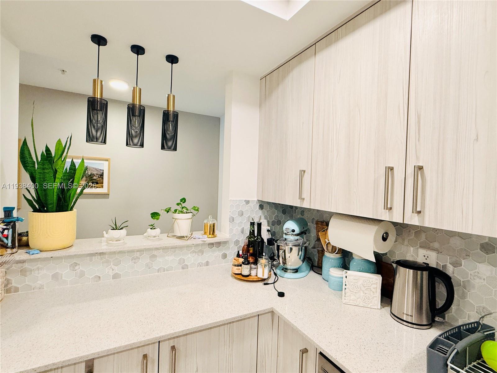 A kitchen features light wood cabinets, white quartz countertops, and a hexagonal tile backsplash — 10950 NW 82nd St # 104, Doral FL 33178, DORAL, FL