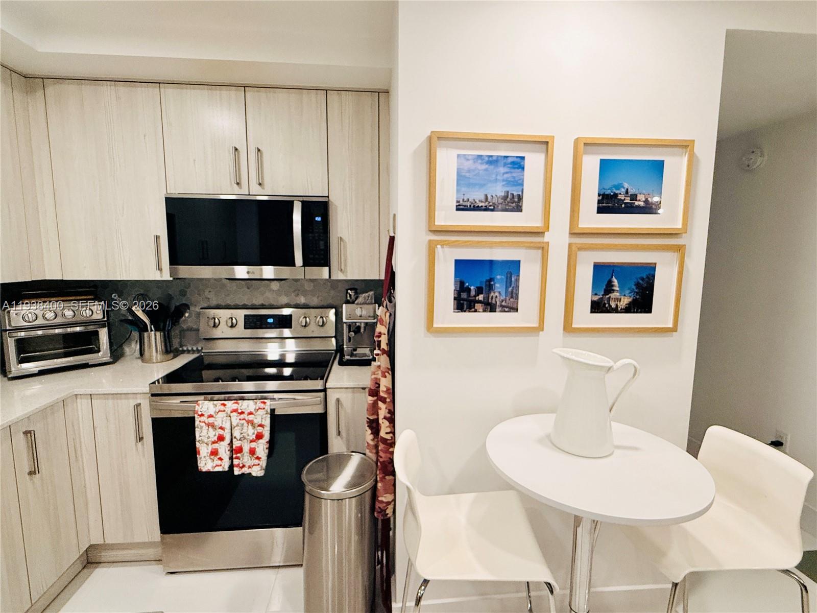 A kitchen features light wood cabinets, stainless steel appliances, and a small white dining table — 10950 NW 82nd St # 104, Doral FL 33178, DORAL, FL