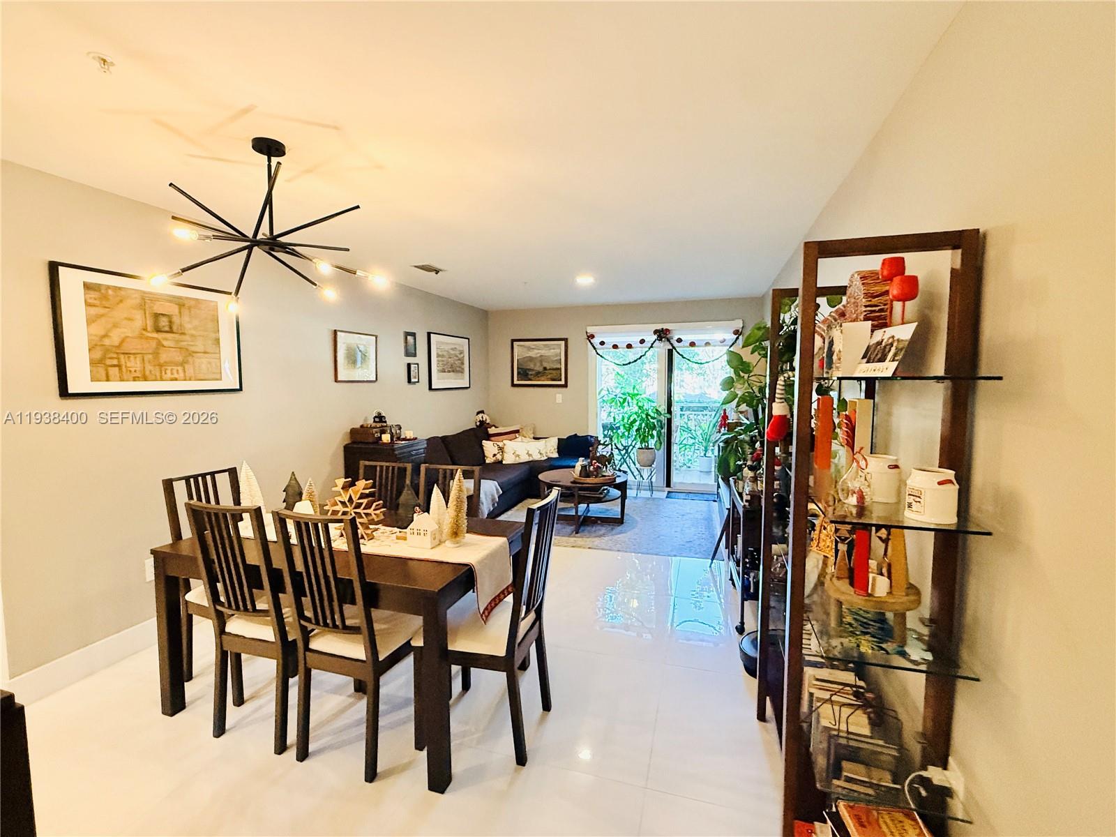 A dining area and living room feature tile flooring, a modern chandelier, and glass shelving — 10950 NW 82nd St # 104, Doral FL 33178, DORAL, FL