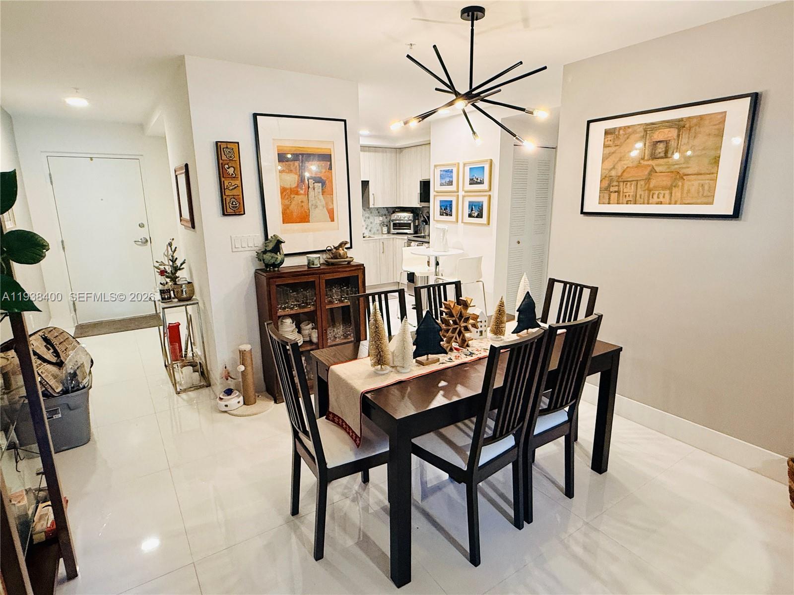 A dining room features a dark wood table, modern chandelier, and tile flooring — 10950 NW 82nd St # 104, Doral FL 33178, DORAL, FL