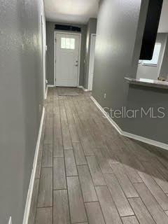 A hallway with gray walls and light wood-look tile flooring leads to a white front door — 5148 MAGNOLIA PRESERVE BOULEVARD, WINTER HAVEN, FL