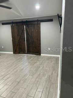 A room with light wood-look tile flooring and dark wood sliding barn doors on a track — 5148 MAGNOLIA PRESERVE BOULEVARD, WINTER HAVEN, FL