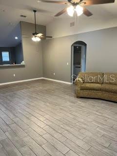 A living room features gray wood-look tile flooring, a ceiling fan, and a beige sofa — 5148 MAGNOLIA PRESERVE BOULEVARD, WINTER HAVEN, FL