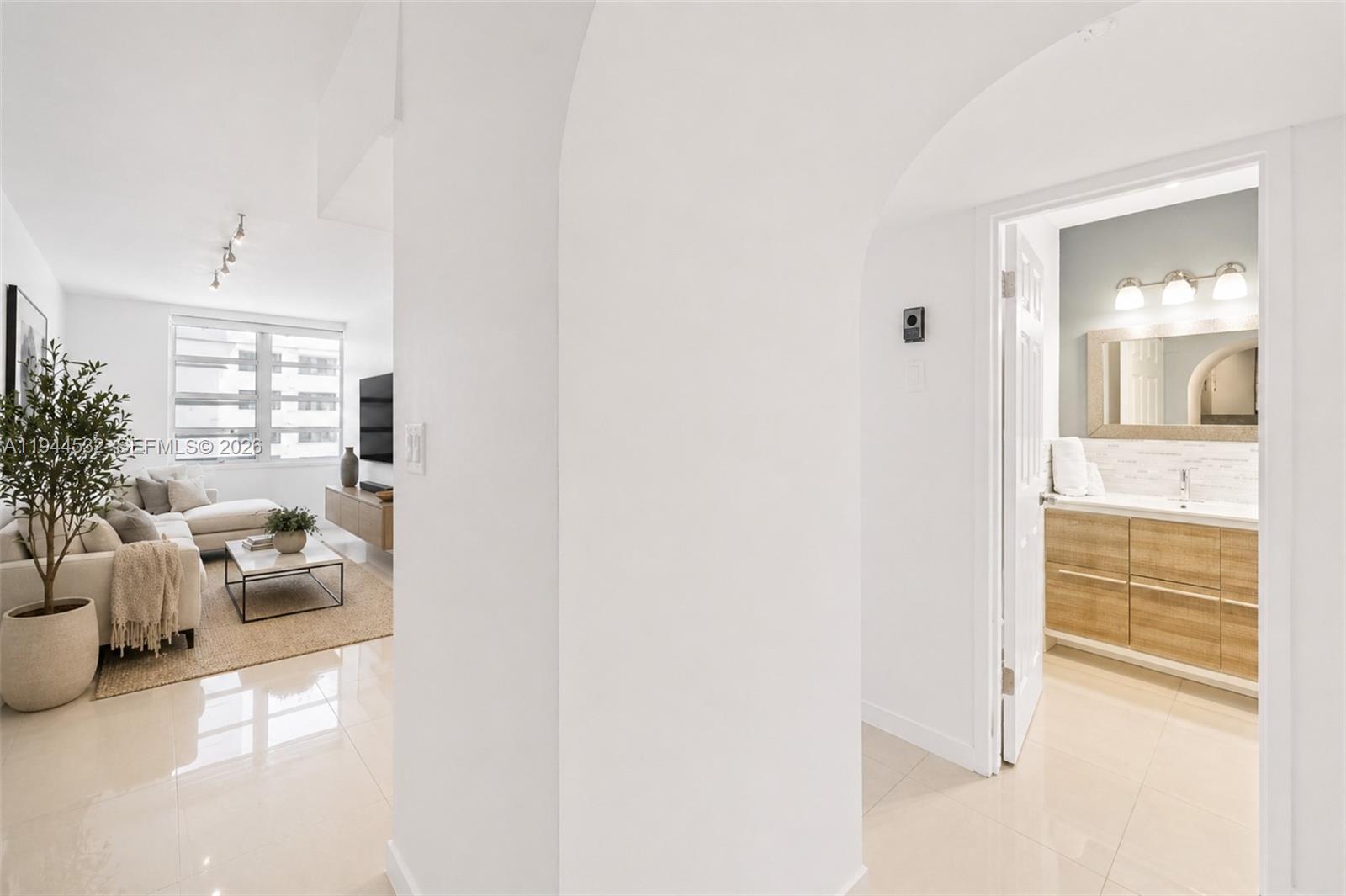 A white hallway leads to a bathroom on the right and a living room beyond — 100 Lincoln Rd # 501, Miami Beach FL 33139, MIAMI BEACH, FL