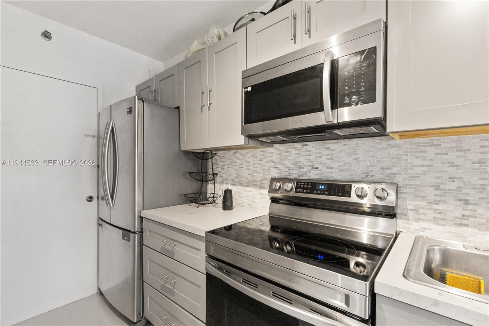 A kitchen features stainless steel appliances, light gray cabinetry, and a white tiled backsplash — 100 Lincoln Rd # 501, Miami Beach FL 33139, MIAMI BEACH, FL