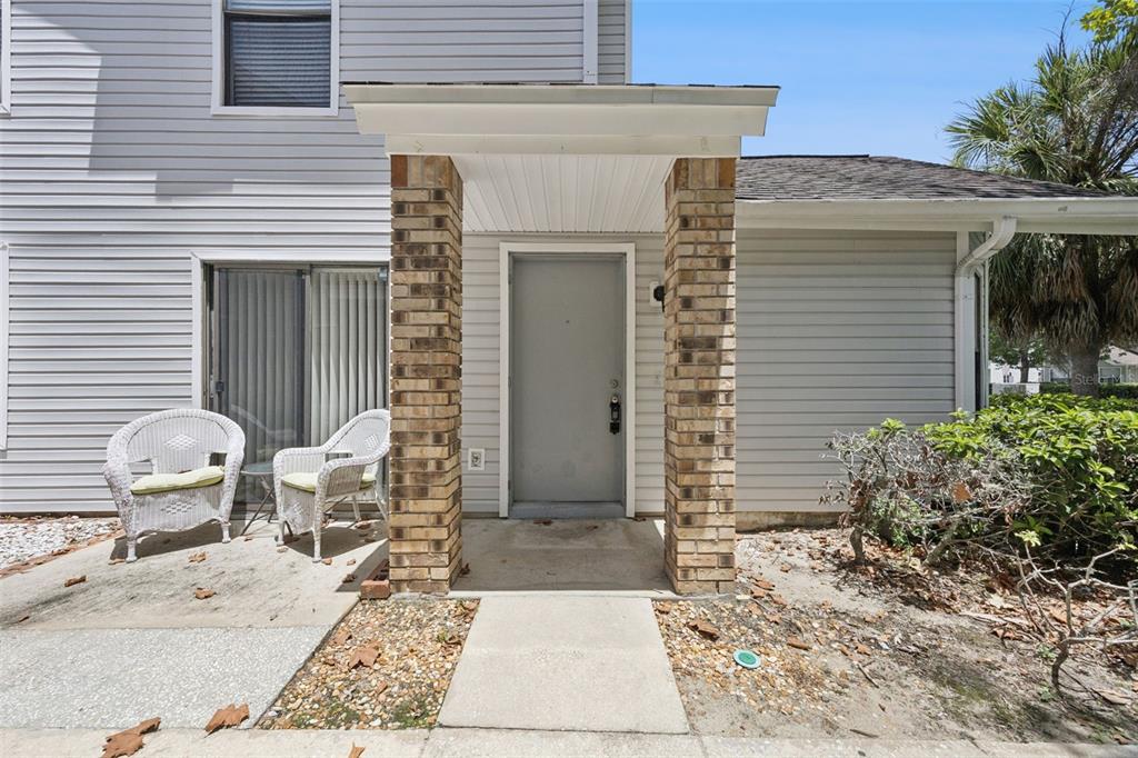 The exterior of a house features a gray front door under a brick-columned porch — 3023 RIO GRANDE TRAIL UNIT 3023, KISSIMMEE, FL