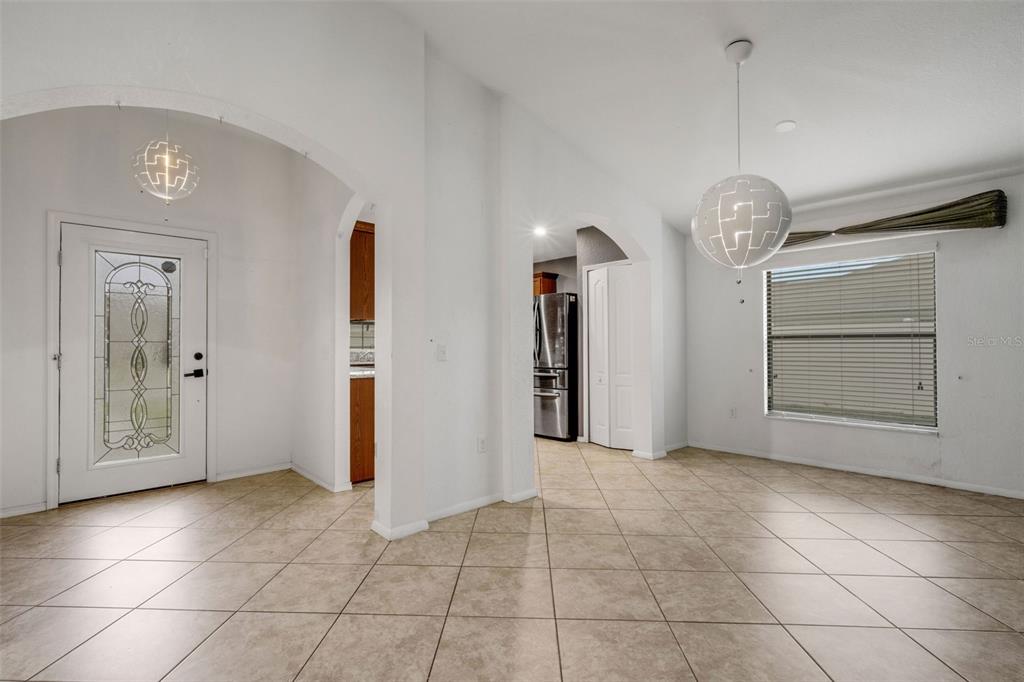 An interior view shows a tiled dining area with two modern globe pendant lights — 1712 CHARMI DRIVE, LAKELAND, FL