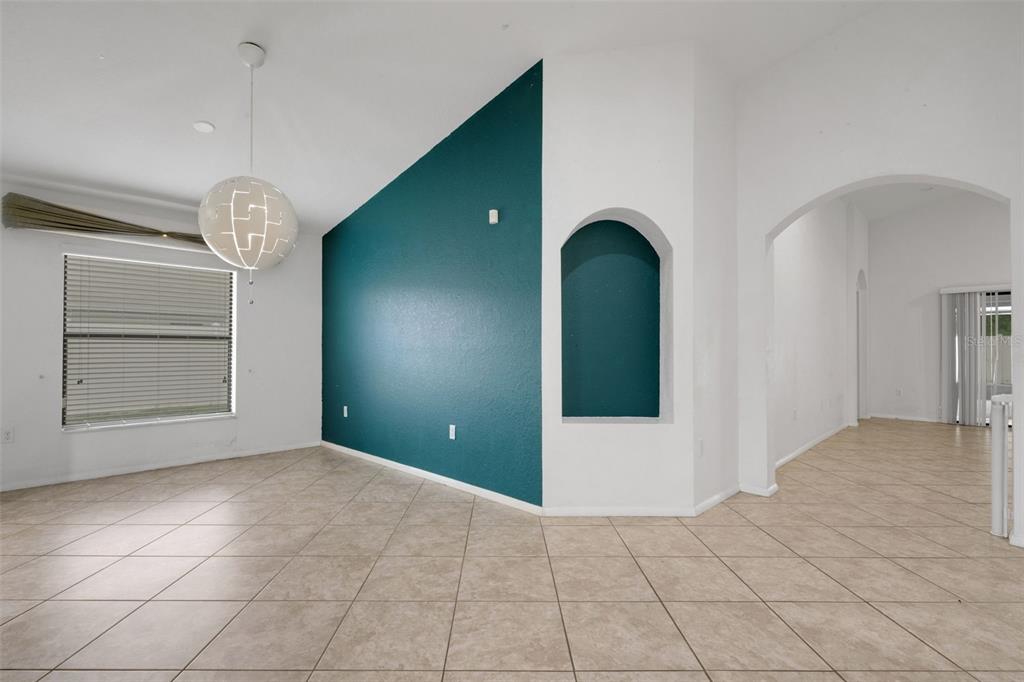 An empty room features beige tile floors, white walls, and a teal accent wall — 1712 CHARMI DRIVE, LAKELAND, FL
