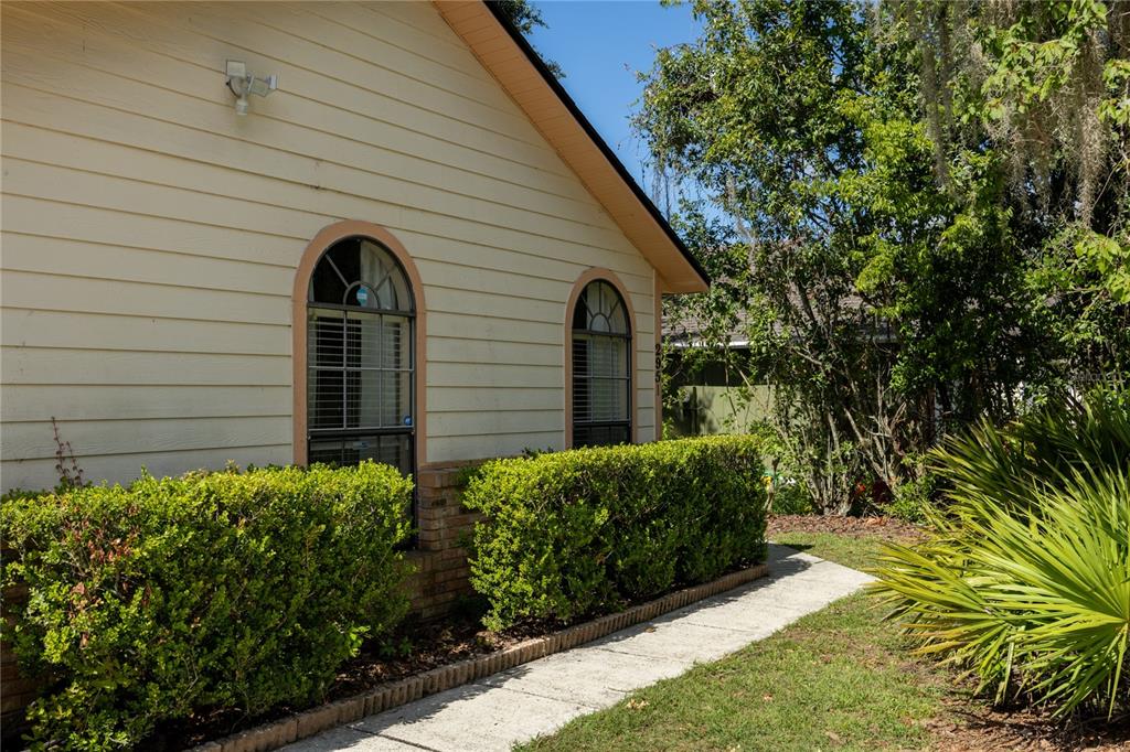 The exterior of a house features light-colored siding, two arched windows, and a manicured hedge — 2951 SW 40TH AVENUE, GAINESVILLE, FL