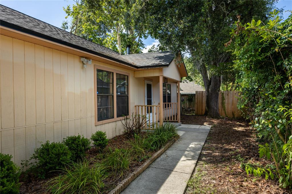 A side view of a tan house with a concrete walkway and a small porch — 2951 SW 40TH AVENUE, GAINESVILLE, FL