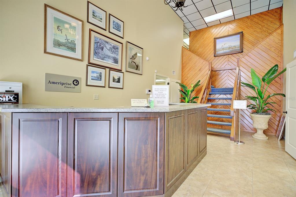 A reception area features a wooden desk, a staircase with wood paneling, and framed artwork — 4927 SOUTHFORK DRIVE, LAKELAND, FL