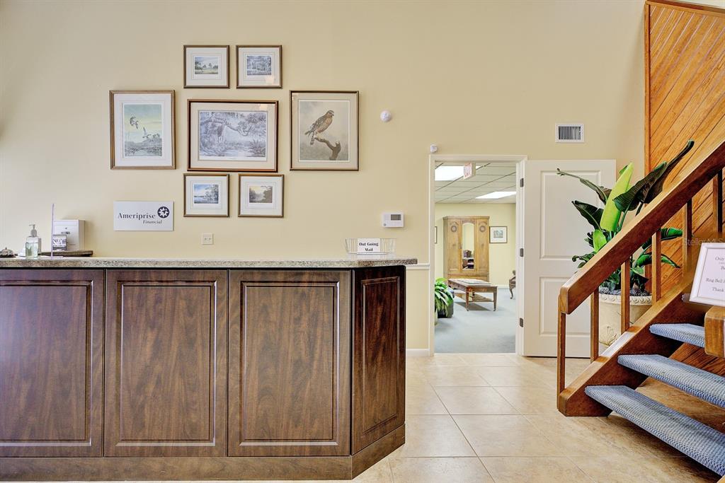 A reception area features a dark wood desk, a gallery wall, and a wooden staircase — 4927 SOUTHFORK DRIVE, LAKELAND, FL