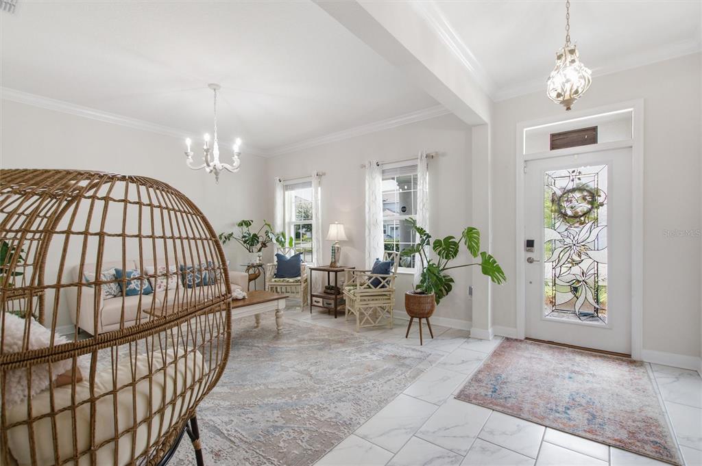 A bright living room features a rattan egg chair, white tile floors, and a glass-paneled door — 1458 OLYMPIC CLUB BOULEVARD, DAVENPORT, FL