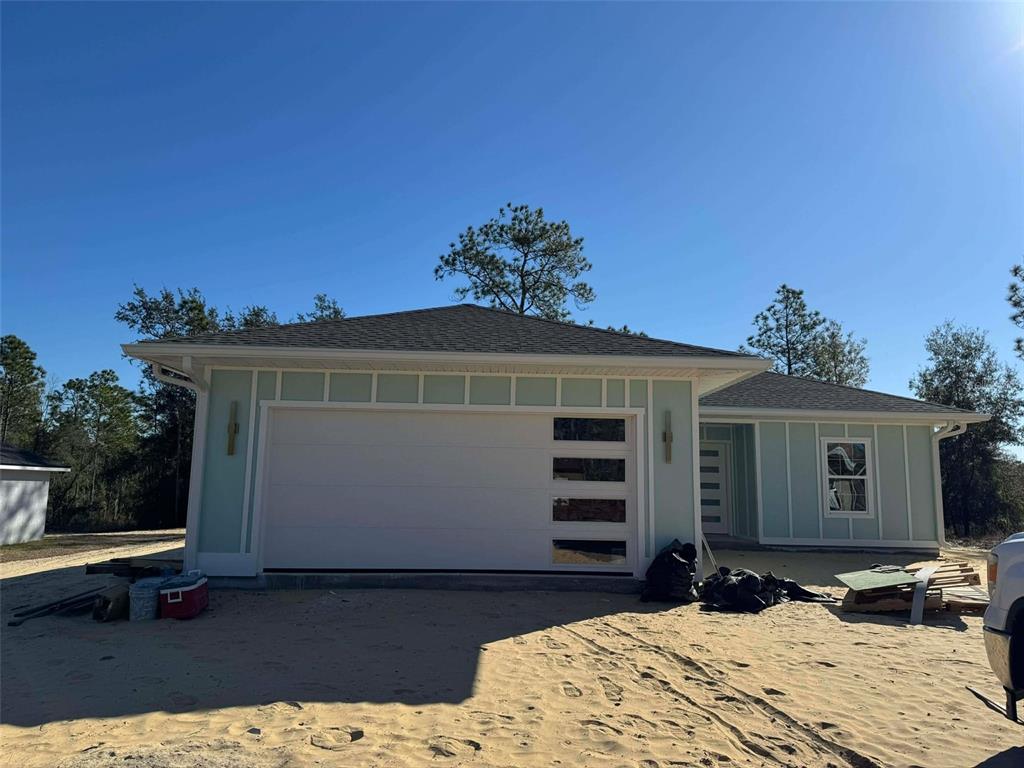 A light green house with a modern garage door and board-and-batten siding under construction — 1471 NE 153RD AVENUE, WILLISTON, FL