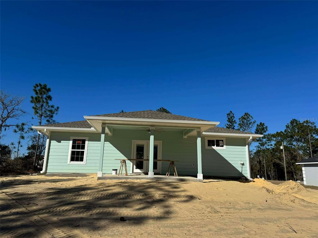 The exterior of a light green house features a covered porch and a sandy yard — 1471 NE 153RD AVENUE, WILLISTON, FL
