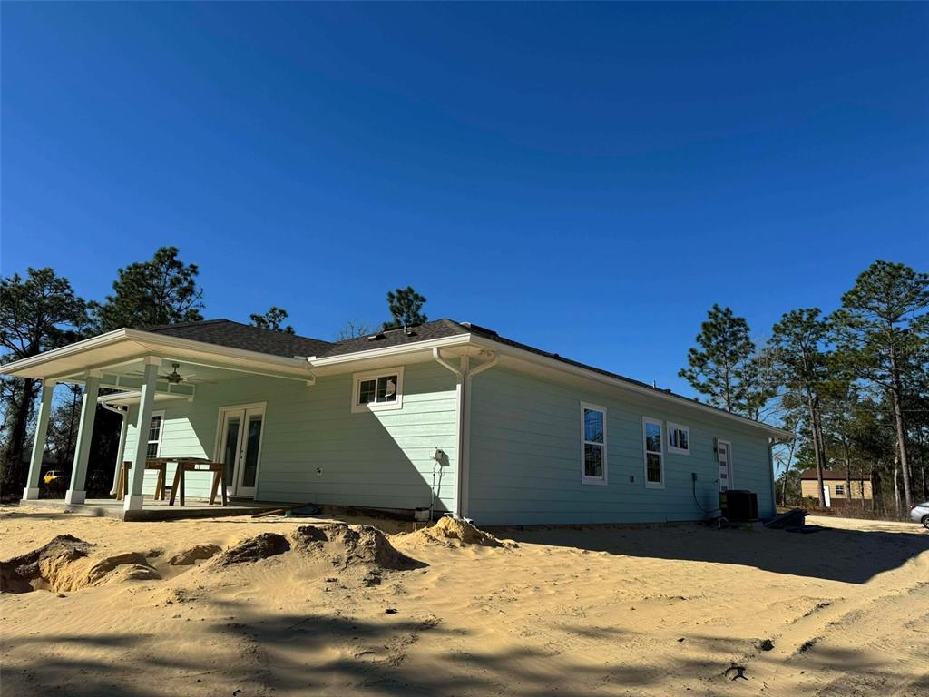 The exterior of a light green house features a covered patio and sandy ground — 1471 NE 153RD AVENUE, WILLISTON, FL