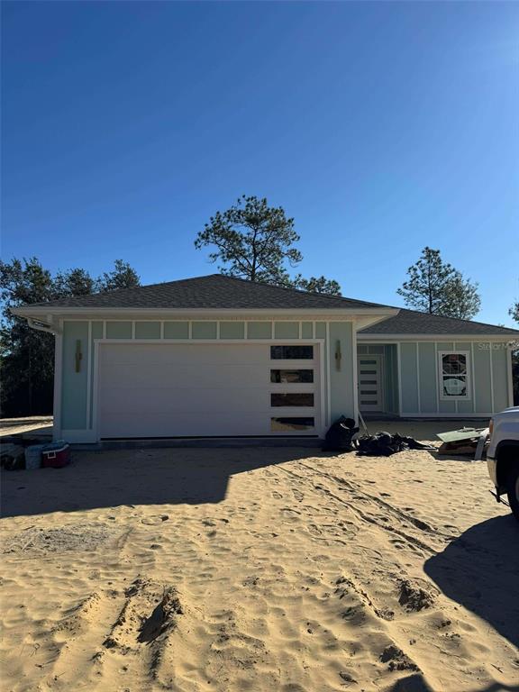 A light green single-story house with a modern garage door and a sandy front yard — 1471 NE 153RD AVENUE, WILLISTON, FL
