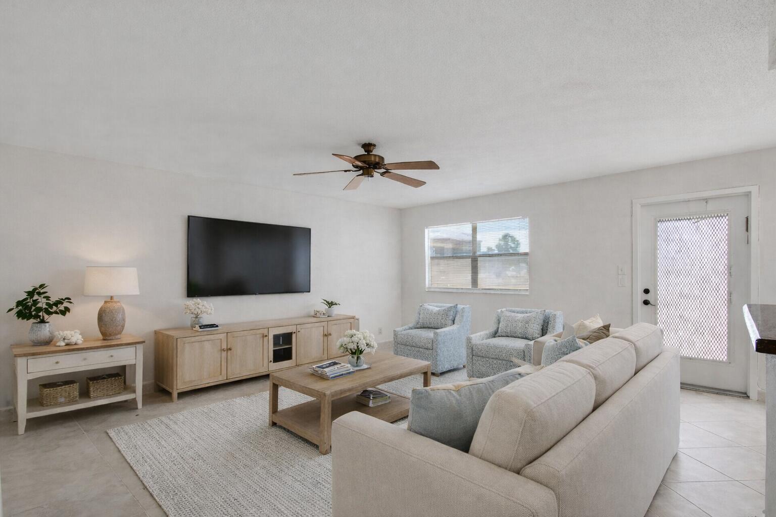 A living room features a beige sofa, two patterned armchairs, a television, and wood furniture — 228 Brittany E, Delray Beach FL 33446, DELRAY BEACH, FL