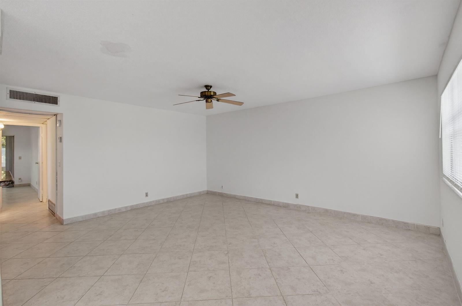 An empty room with white walls, tile flooring, and a ceiling fan — 228 Brittany E, Delray Beach FL 33446, DELRAY BEACH, FL