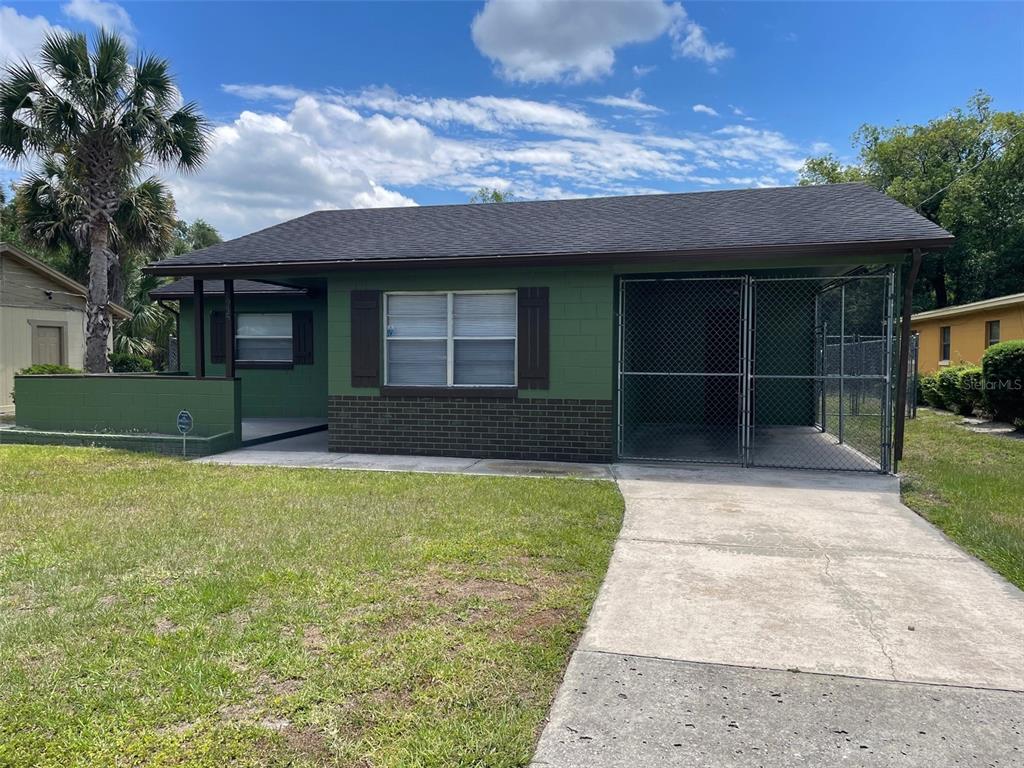 A green single-story house with a front porch, a chain-link carport, and a concrete driveway — 1935 W 14TH STREET, SANFORD, FL