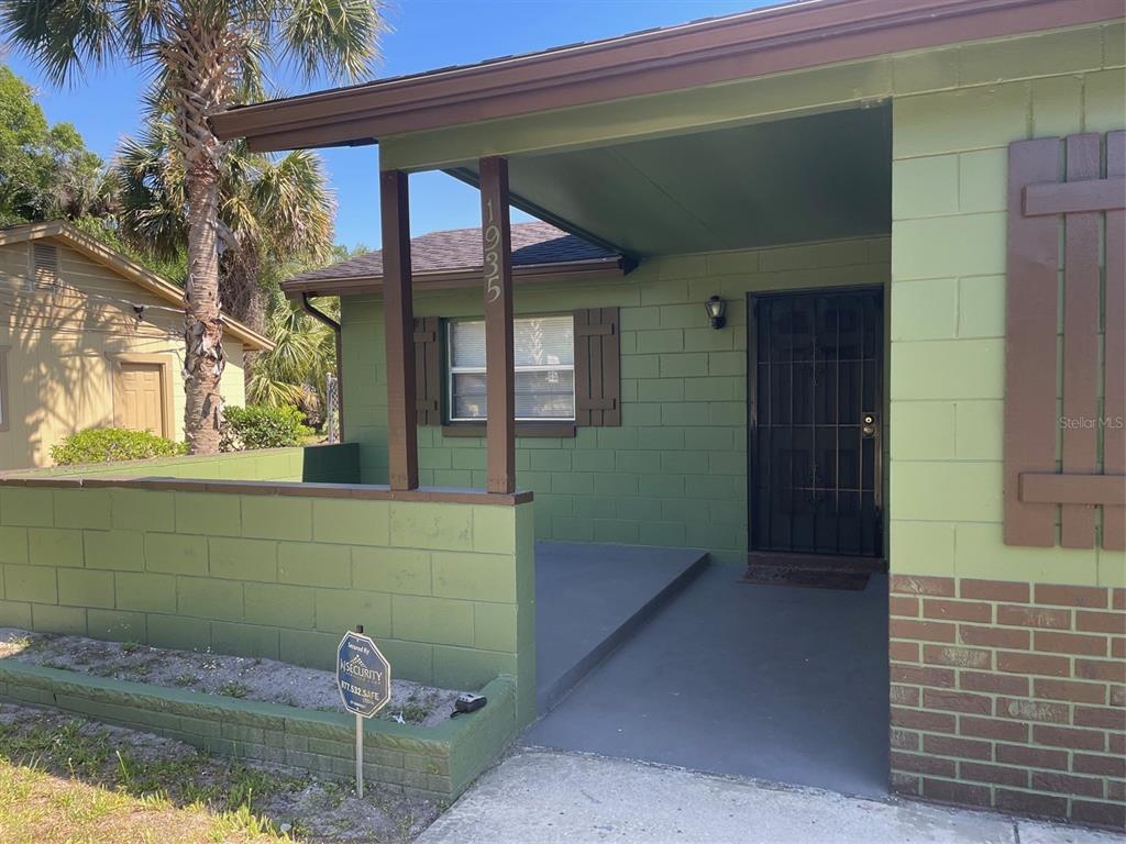 A green concrete block house features a covered front porch and a low perimeter wall — 1935 W 14TH STREET, SANFORD, FL