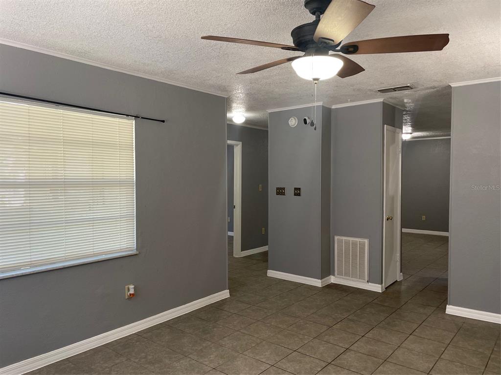 A gray-walled room features tile flooring, a ceiling fan, and doorways leading to other areas — 1935 W 14TH STREET, SANFORD, FL