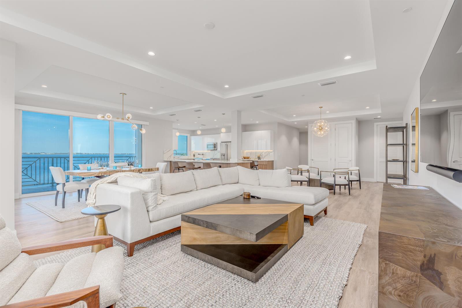 An open-concept living and dining area features a white sectional, wood coffee table, and balcony — 41 SW Seminole Street # 306, Stuart FL 34994, STUART, FL
