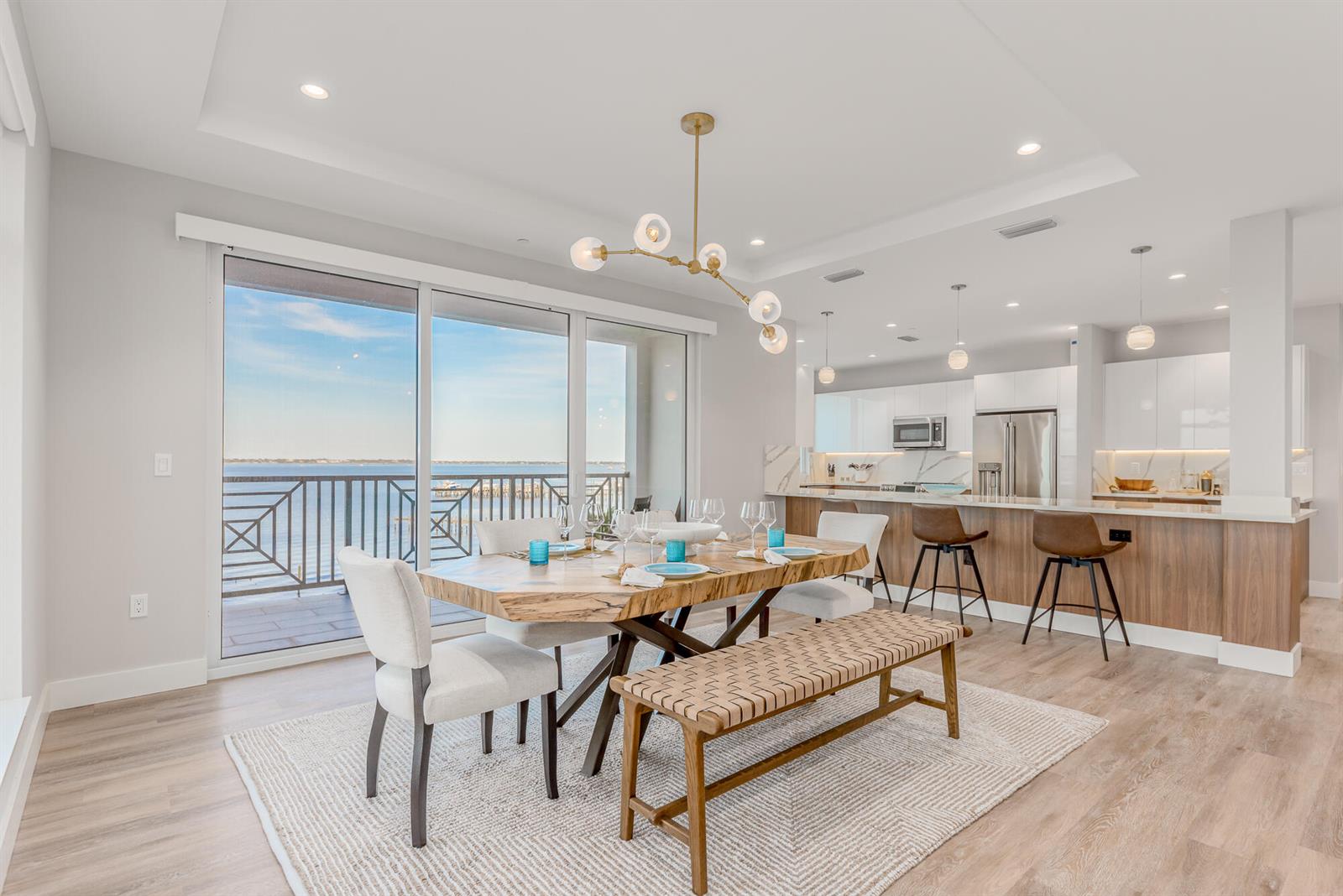 A dining area with a live-edge table and bench overlooks a balcony and water view — 41 SW Seminole Street # 306, Stuart FL 34994, STUART, FL