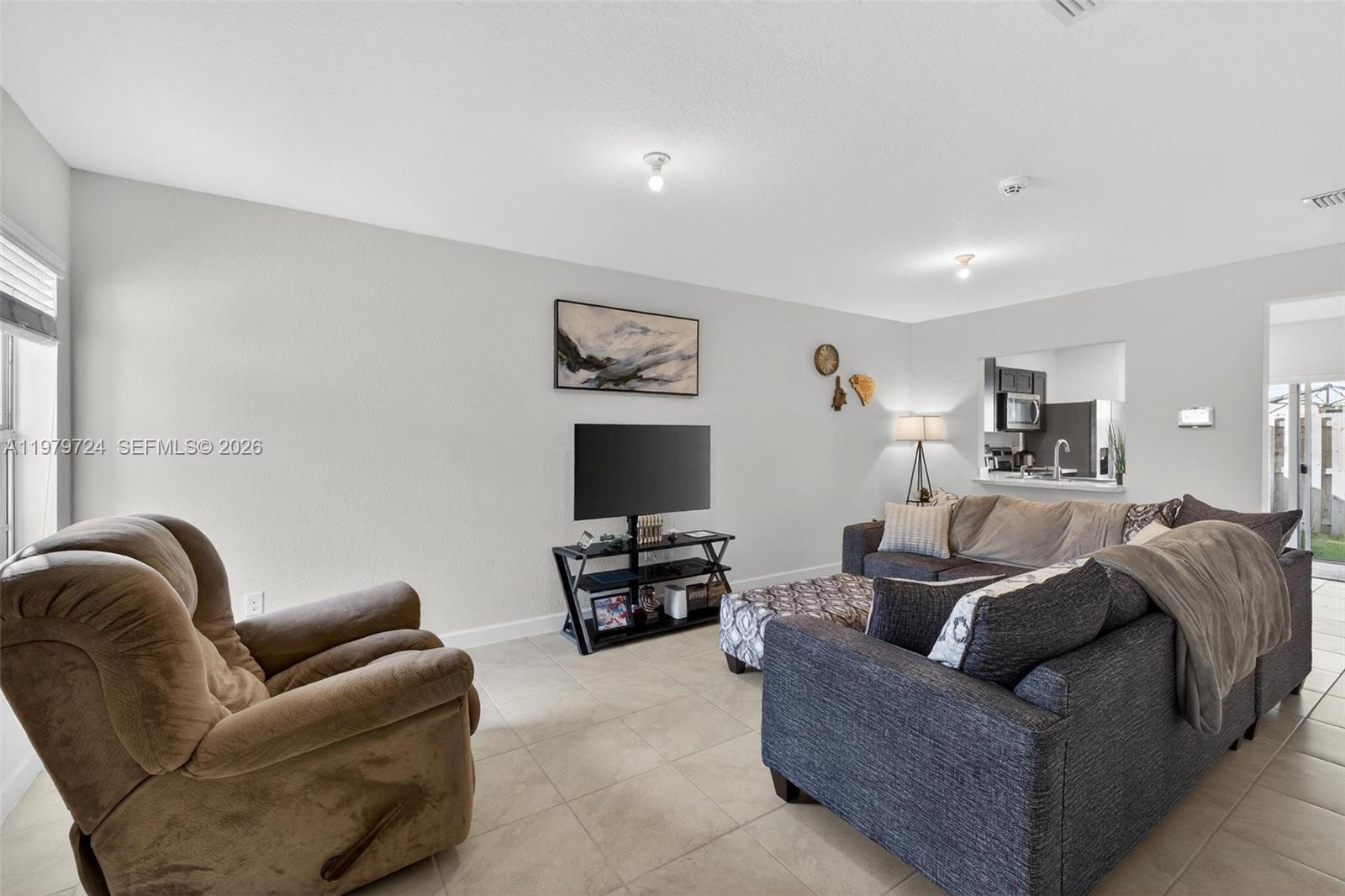 A living room features a brown recliner, a dark sofa, and a television on a stand — 476 NE 4th Ln, Florida City FL 33034, FLORIDA CITY, FL
