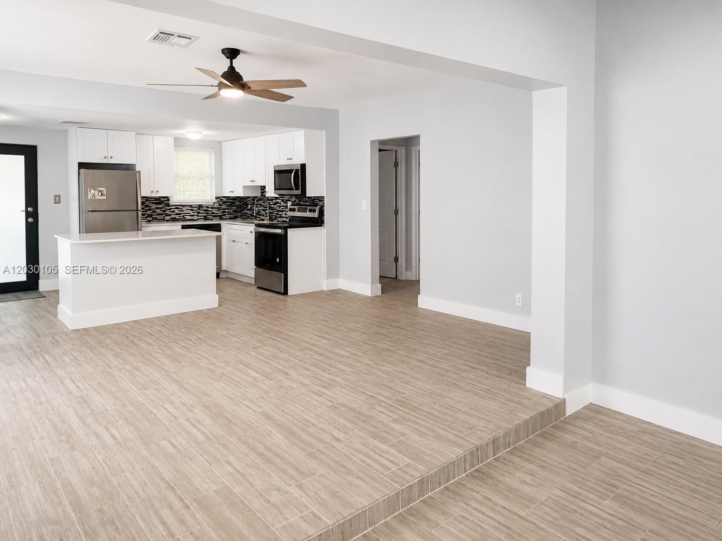 A kitchen with white cabinets and a breakfast bar overlooks a sunken living area — 209 SW 5th St # 209, Dania Beach FL 33004, DANIA BEACH, FL