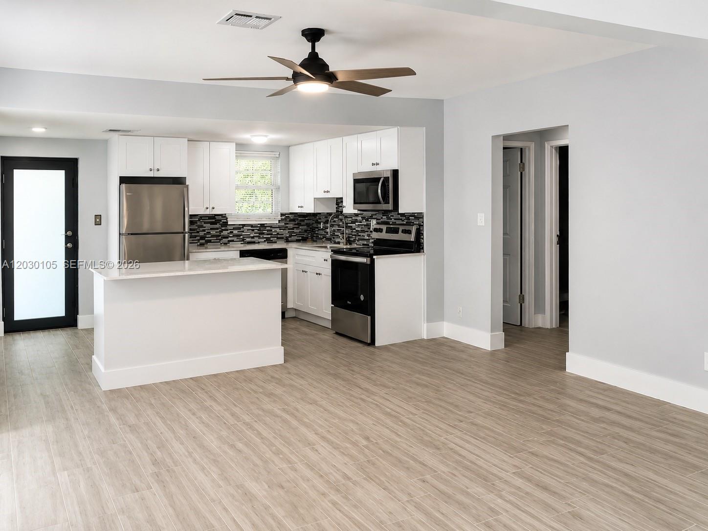 A kitchen with white cabinets, stainless steel appliances, and light wood-look flooring — 209 SW 5th St # 209, Dania Beach FL 33004, DANIA BEACH, FL