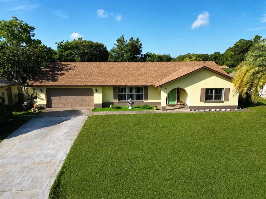 A single-story house with a brown shingled roof, yellow exterior, and a large front lawn — 10 BLACKBURN PLACE, PALM COAST, FL