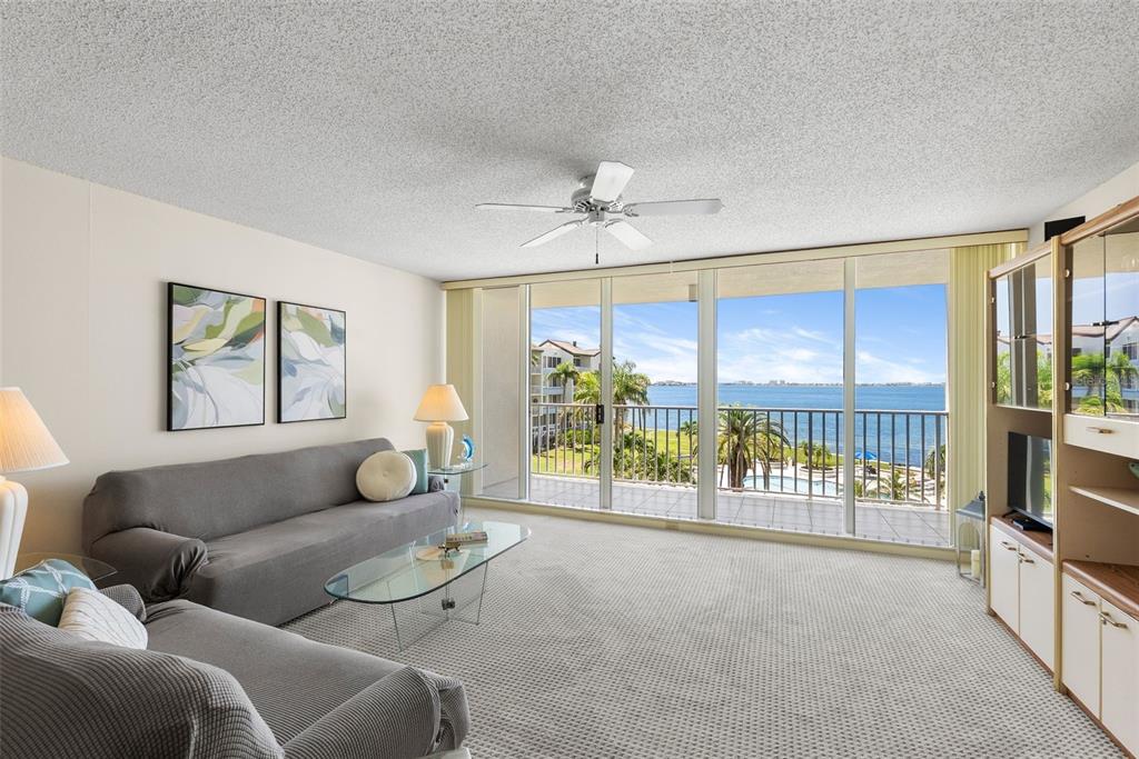 A living room with gray sofas, a glass coffee table, and a balcony overlooking water — 5155 ISLA KEY BOULEVARD S UNIT 304, ST PETERSBURG, FL