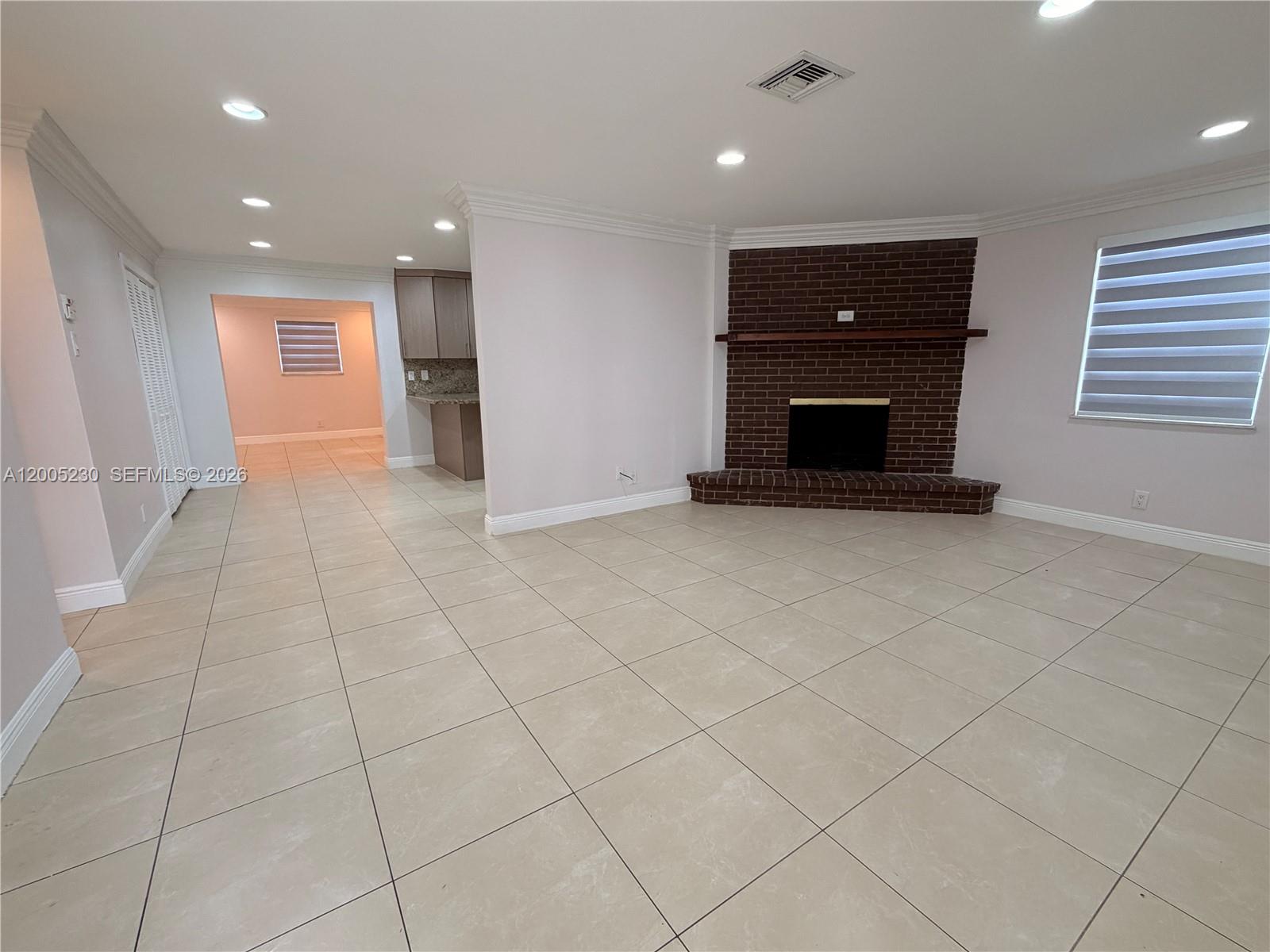 A living room features light-colored tile floors, recessed lighting, and a corner brick fireplace — 3011 N 74th Ave, Hollywood FL 33024, HOLLYWOOD, FL