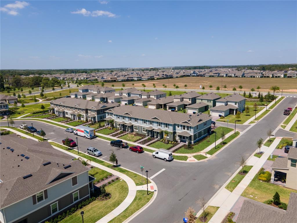 An aerial view shows multi-family townhomes with attached garages and driveways in a suburban neighborhood — 12007 HOLYSTONE STREET, WINTER GARDEN, FL
