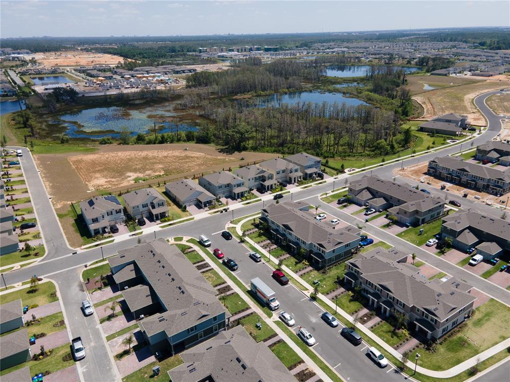 An aerial view shows a suburban neighborhood with multi-family homes, streets, and nearby ponds — 12007 HOLYSTONE STREET, WINTER GARDEN, FL