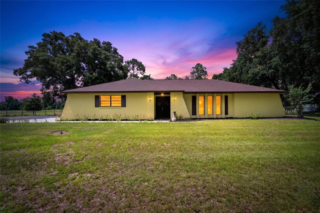 A yellow single-story house with a dark roof stands on a grassy lot at sunset — 3708 JOE SANCHEZ RD, PLANT CITY, FL