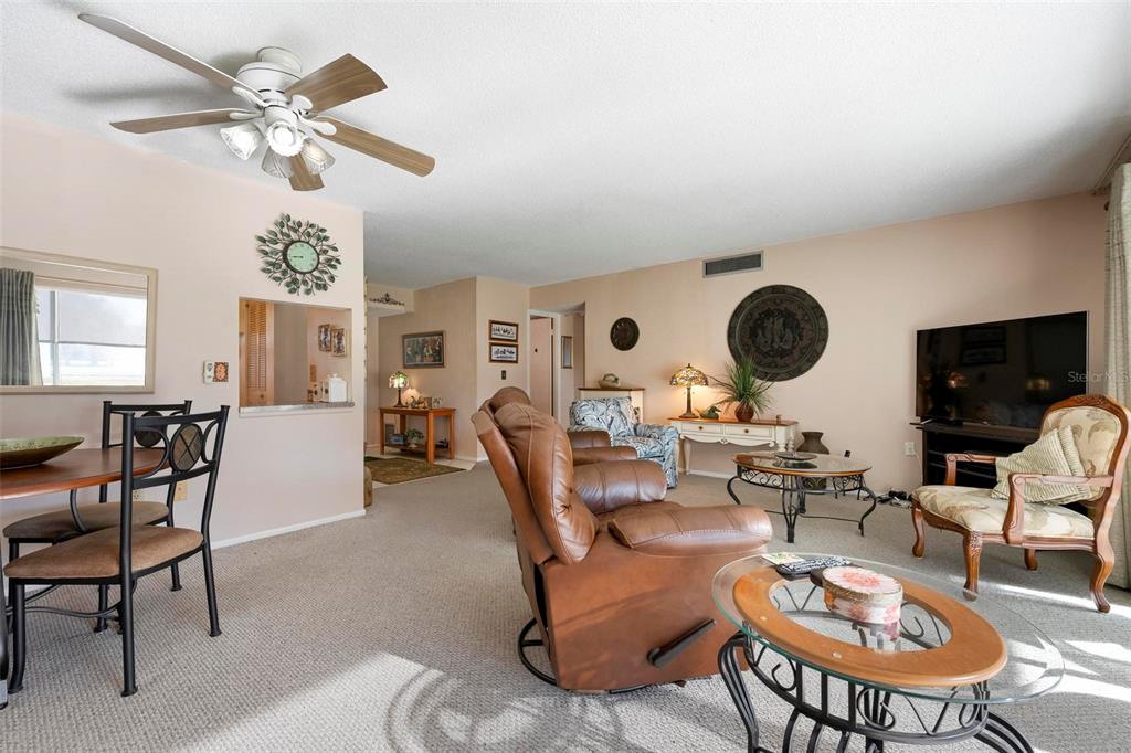 A living room with carpeted floors, a ceiling fan, a dining area, and leather furniture — 4040 IRONWOOD CIRCLE UNIT 102F, BRADENTON, FL