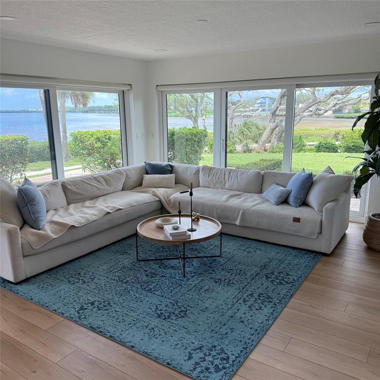 A living room features a large sectional sofa, a round coffee table, and expansive water views — 306 MARINER DRIVE UNIT 306, TARPON SPRINGS, FL