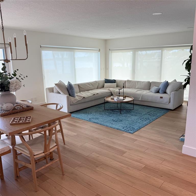 A living and dining area features light wood floors, a large sectional sofa, and blue rug — 306 MARINER DRIVE UNIT 306, TARPON SPRINGS, FL