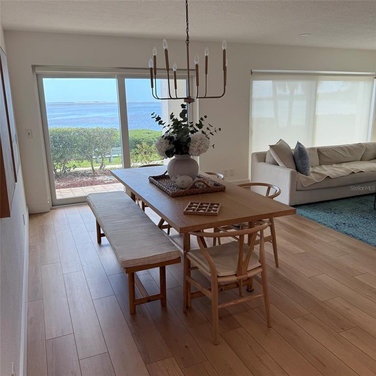 A dining area with a wooden table, bench, and chairs overlooks a coastal water view — 306 MARINER DRIVE UNIT 306, TARPON SPRINGS, FL