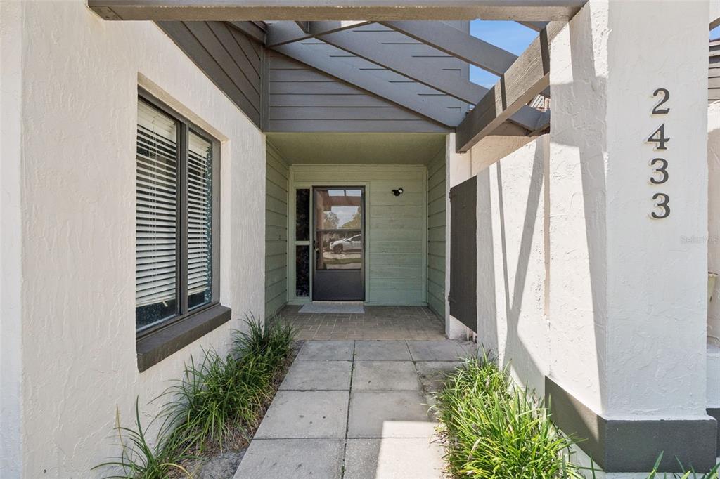 A paved walkway leads to the front entrance of a house with a covered porch — 2433 GRAND TETON CIRCLE, WINTER PARK, FL