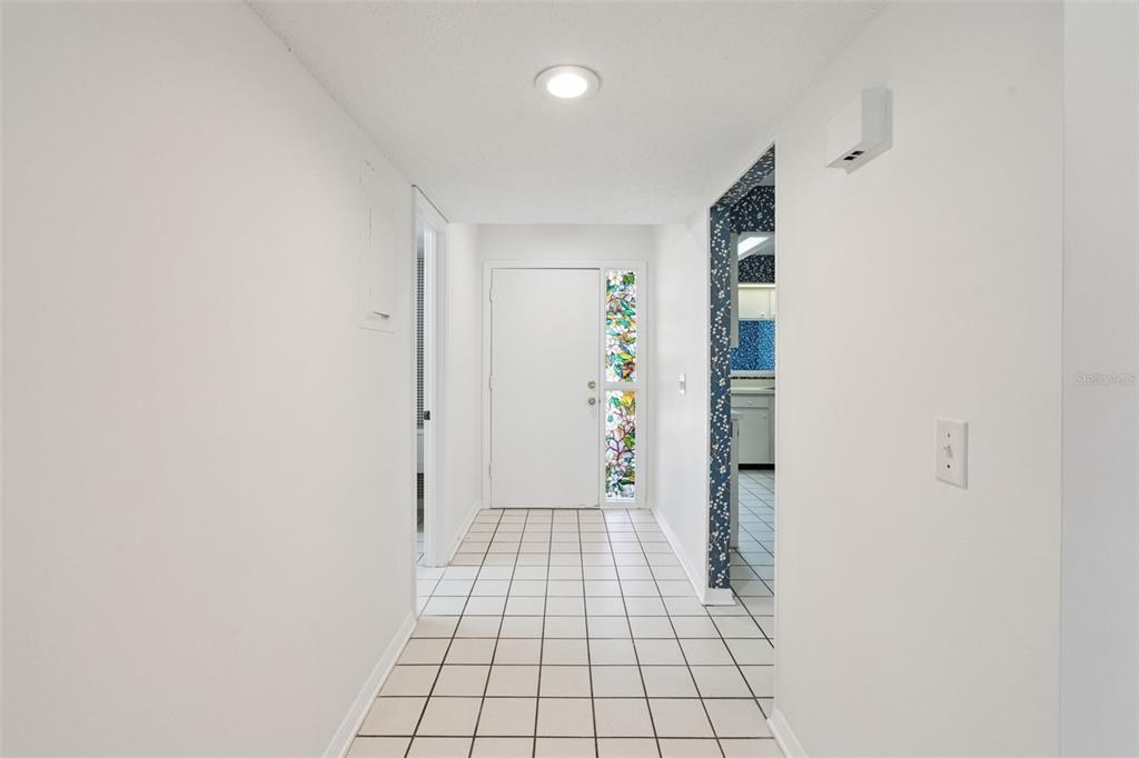 A white-walled entryway features a tiled floor, a front door with stained glass, and lighting — 2433 GRAND TETON CIRCLE, WINTER PARK, FL
