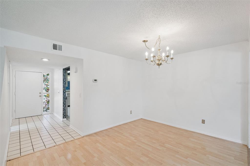 A dining area features light wood-look flooring, white walls, and a traditional chandelier — 2433 GRAND TETON CIRCLE, WINTER PARK, FL