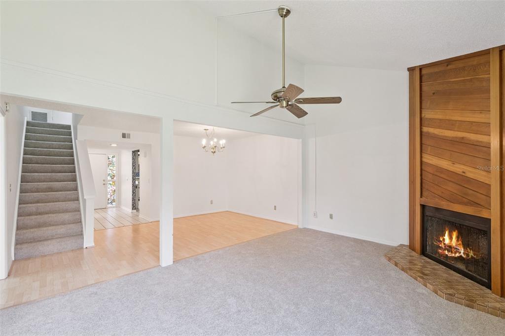 A living room with a fireplace, wood accent wall, and an adjacent dining area — 2433 GRAND TETON CIRCLE, WINTER PARK, FL