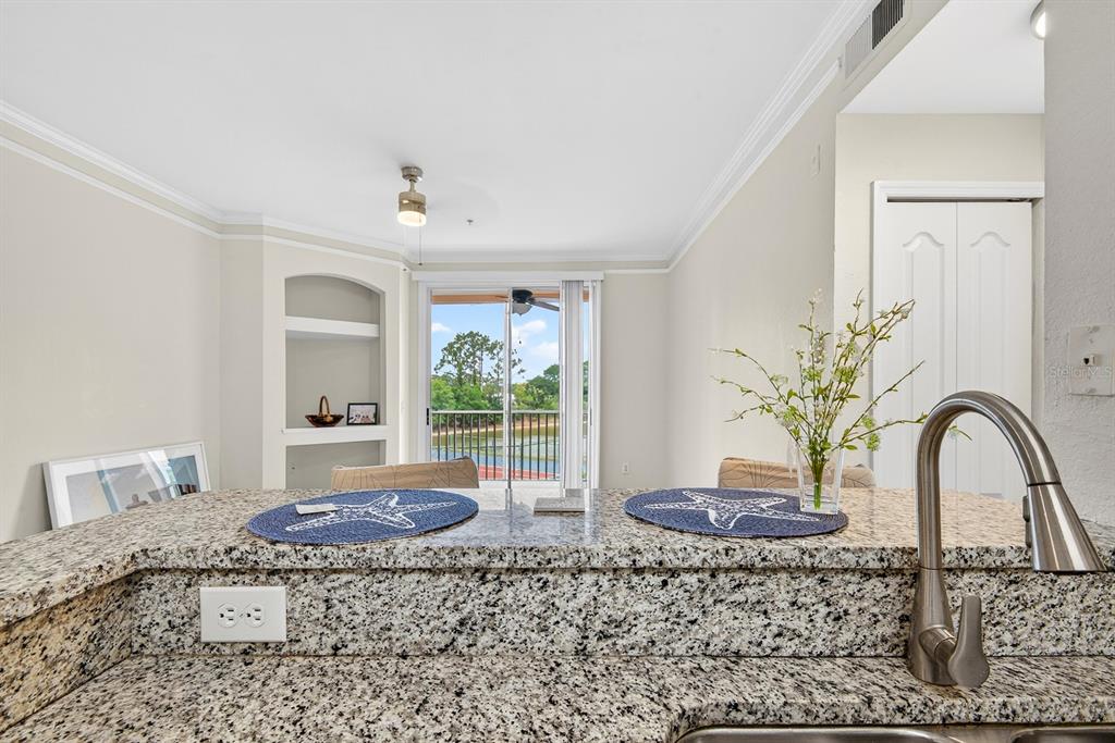 A kitchen counter with granite countertops overlooks a living area with a balcony view — 4142 CENTRAL SARASOTA PARKWAY UNIT 1426, SARASOTA, FL